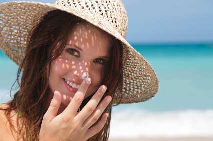 young lady applying sunscreen at the beach